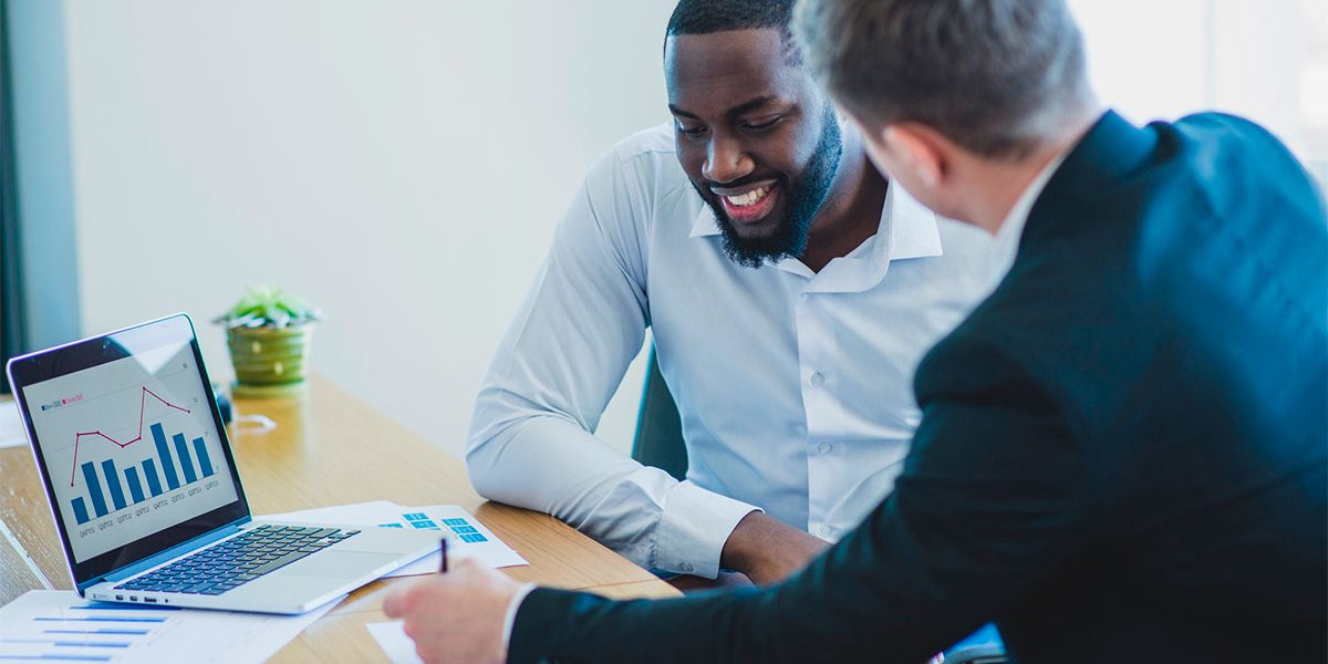 Marketing-Conversacional—Destaque Dois homens fazendo o planejamento de marketing conversacional na mesa do escritório com o notebook e papéis.